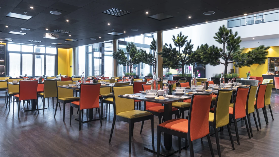 Frokostsal med gule og orange stoler og planter på Thon Hotel Nodlys i Bodø sentrum