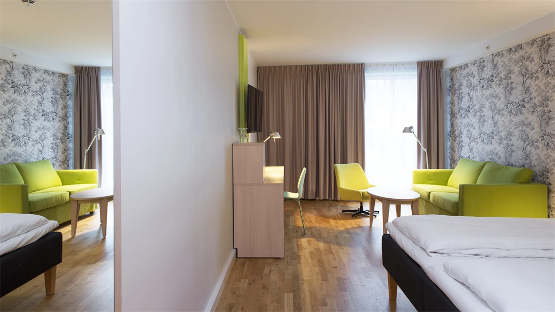 Doppelbett mit Blumentapete, TV-Gerät und Schreibtisch im Familienzimmer im Thon Hotel Sandven in Nordheimsund