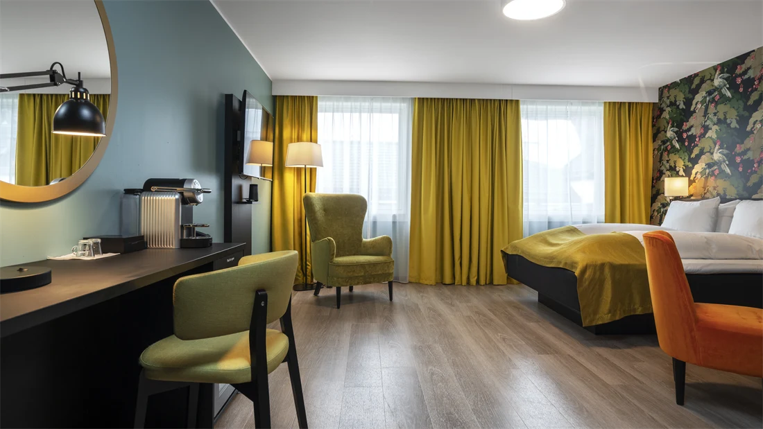 Businessrom hos Thon Hotel Bristol Bergen med skrivepult, TV, store vindusflater, dobbeltseng, lenestoler og Nespresso-maskin. Gulvet er parkettbelagt.