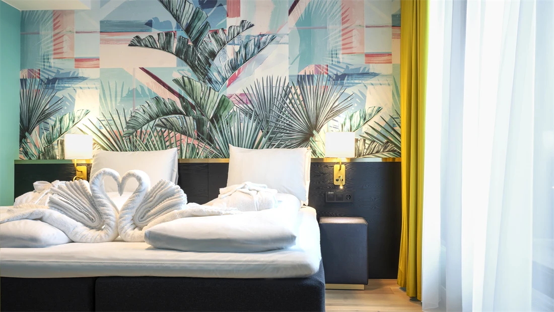 Dobbeltseng med tapet med jungelblader på suite på Thon Hotel Storo i Oslo