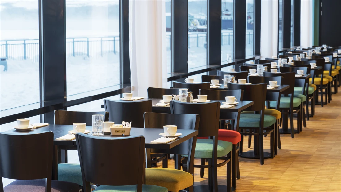 Bord i frokostsal med store vinduer som gir utsikt mot kaia og havet på Thon Hotel Kirkenes ved kaia i Kirkenes sentrum