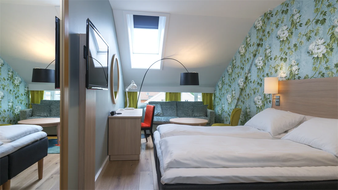 Seng, TV, skrivebord, stol og sofagruppe i superiorrom på Thon Hotel Tønsberg Brygge